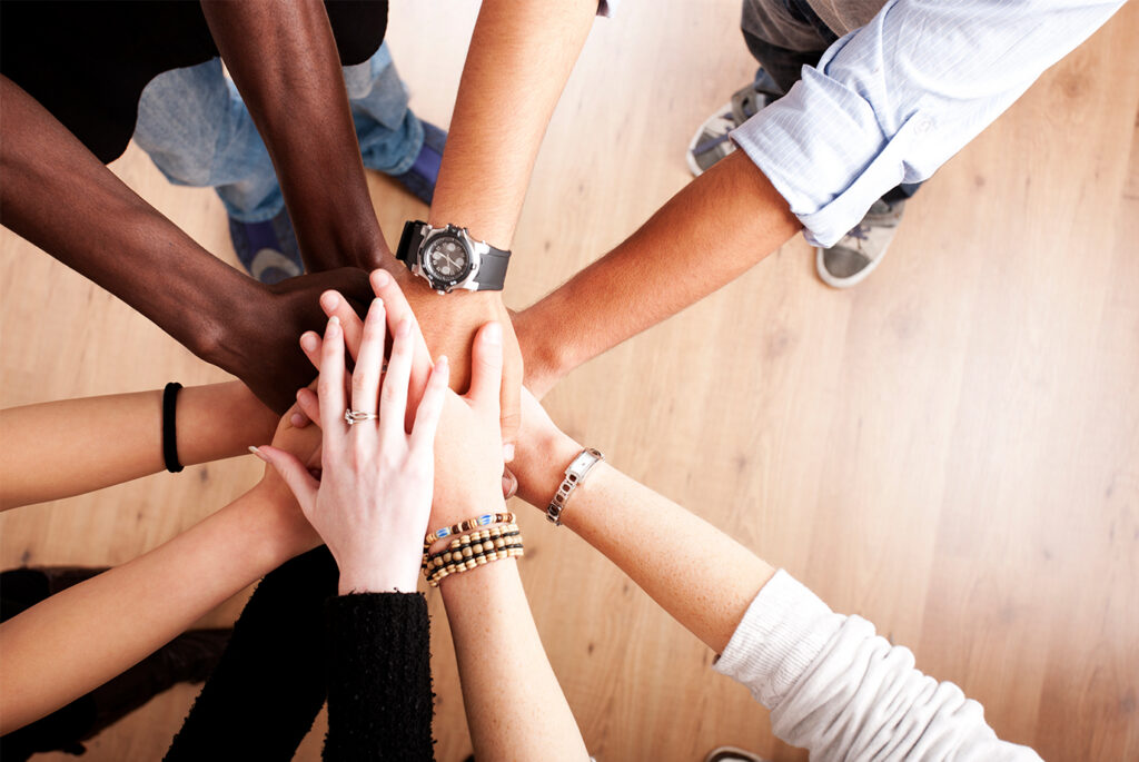 Diverse group of hands joined together in a circle, representing the relationship-driven foundation of publisher development in affiliate marketing partnerships.