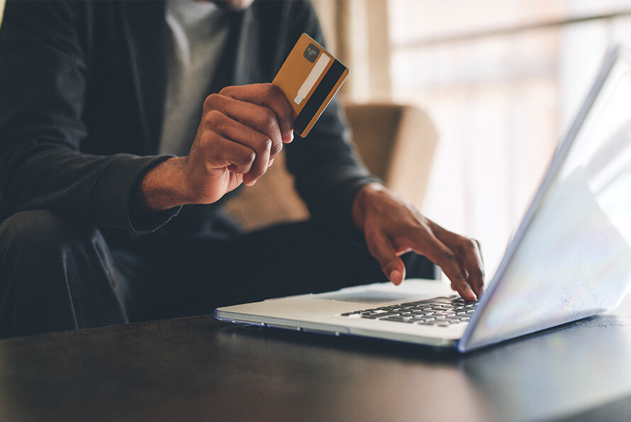 Consumer holding a credit card while shopping online, representing how loyalty affiliate partners incentivize repeat purchases and customer retention.